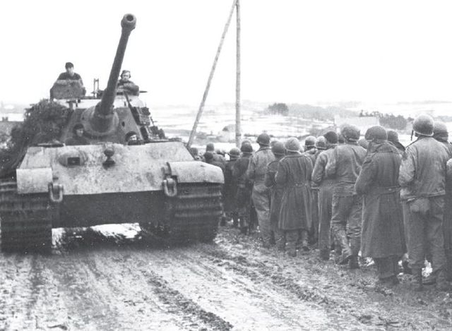 Königstiger del Schwere SS-Panzer-Abteilung 501, agregado al Kampfgruppe Peiper, pasa junto a una columna de prisioneros norteamericanos. Diciembre 1944